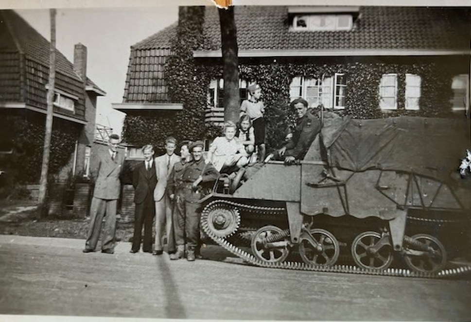 An Allied tracked carrier parked outside the ivy-covered house near Eindhoven where Anita Budding Meyer was hidden, with soldiers and children gathered around it at the liberation