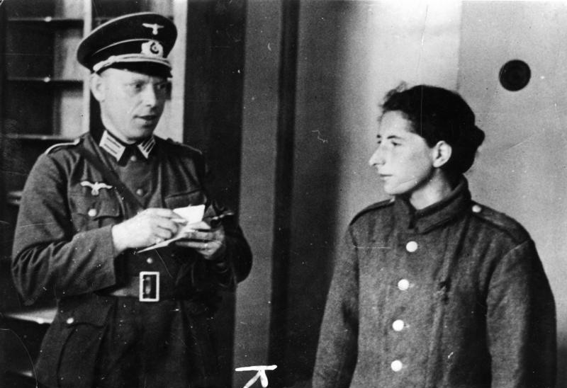 A Jewish woman under arrest in occupied Poland, escorted by German soldiers.