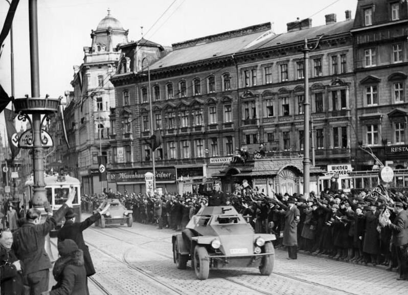 A German armoured scout car and troops moving through a Vienna street in March 1938.