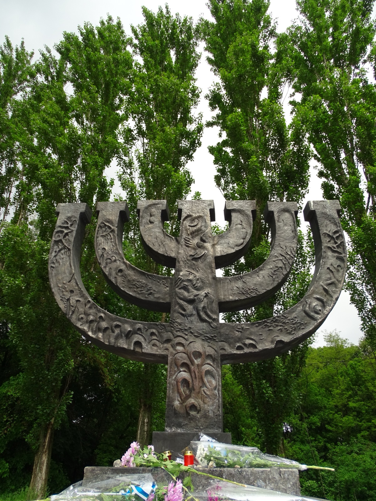 The bronze menorah memorial at Babyn Yar in Kyiv, seen among trees.