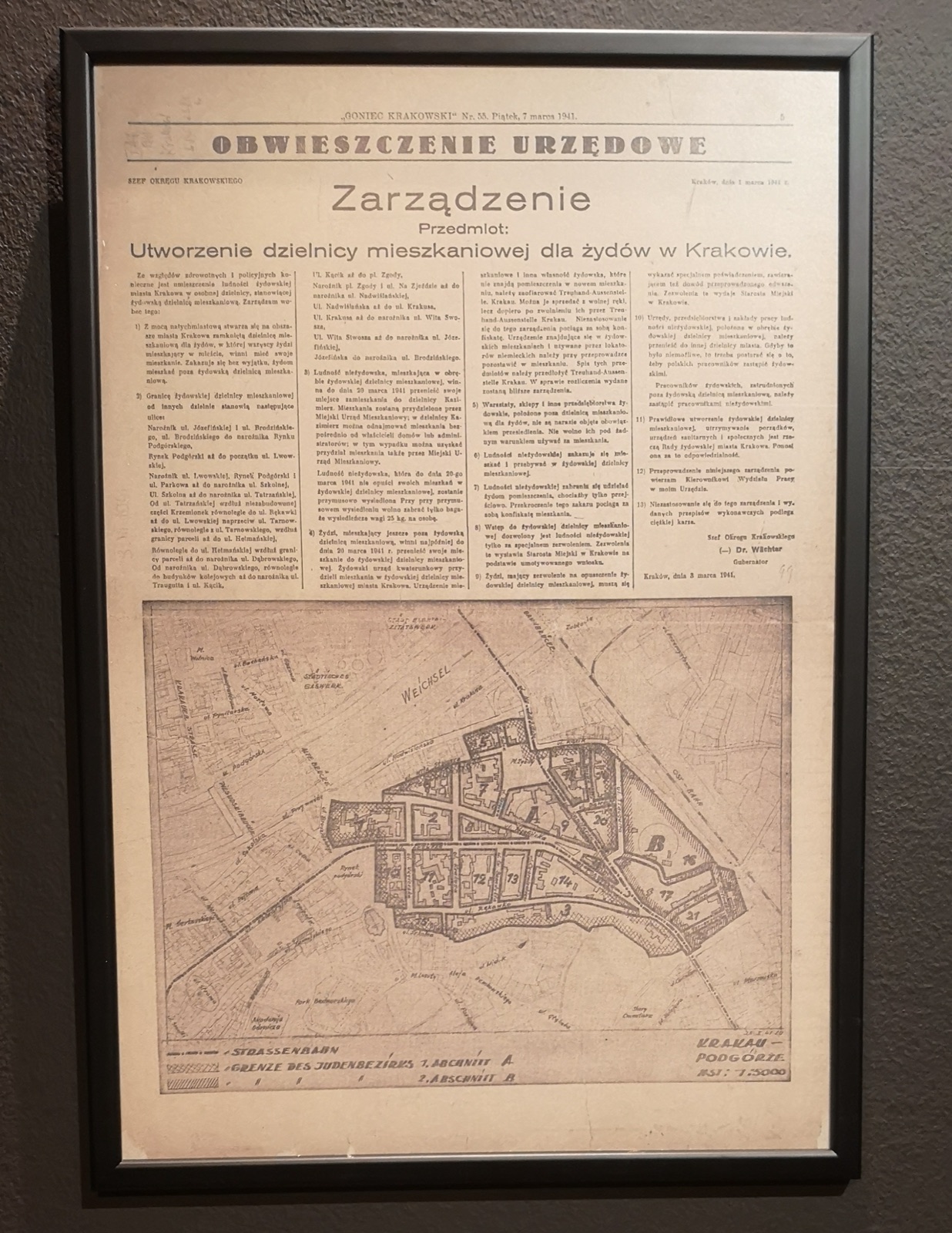 A newspaper page photographed flat, a boxed official notice in dense German and Polish type running down the column.