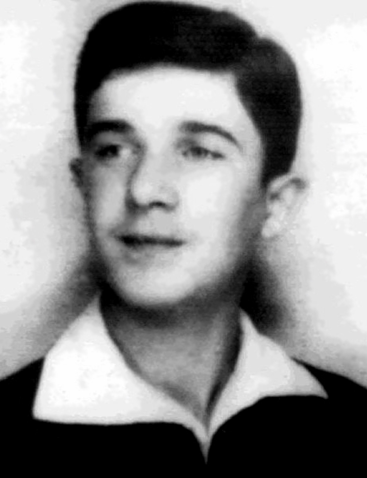 Head-and-shoulders portrait of a young man in a dark jacket and open-collared shirt, looking slightly away from the camera.