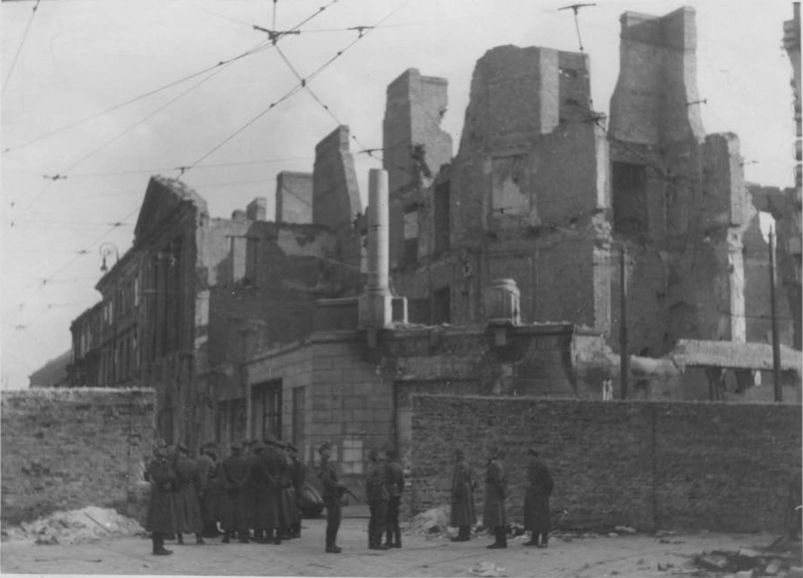 A wide view across a district of burned-out apartment blocks, roofs gone, walls standing open to the sky, rubble filling the streets between them.