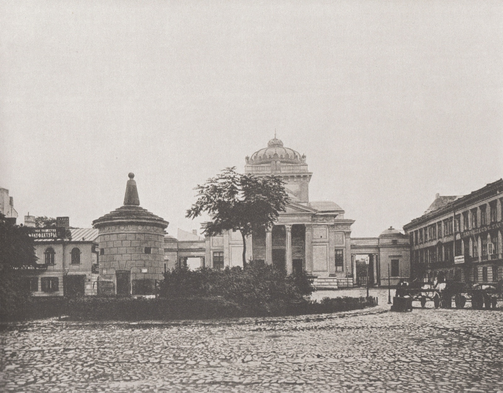 A large domed synagogue in a classical style seen from the street, a columned entrance at the head of a broad flight of steps and low buildings on either side.