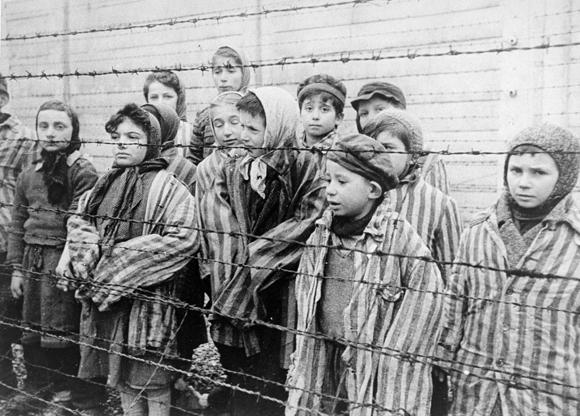 Child survivors of Auschwitz-Birkenau behind barbed wire, filmed after liberation