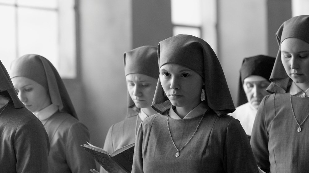 Black and white composition of young nuns in habits, framed low in the corner of a tall empty frame