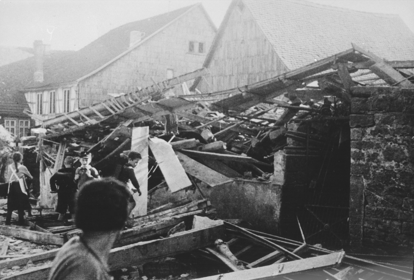 Children standing and clambering on a mound of rubble and broken masonry where a building once stood.