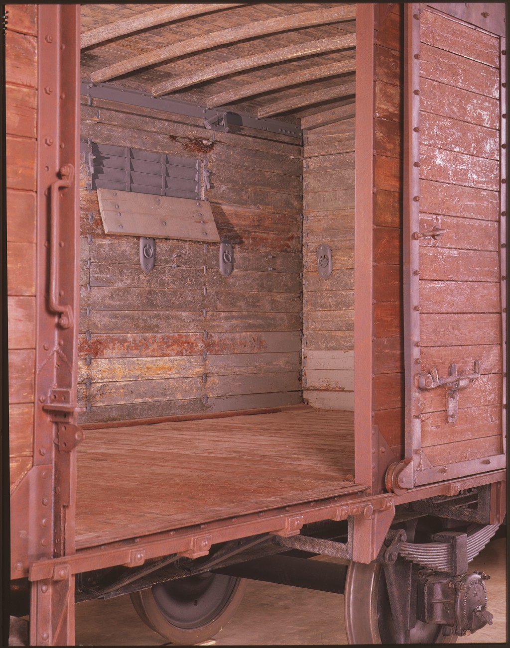 Interior of a wooden cattle car with slats of light coming through the walls.