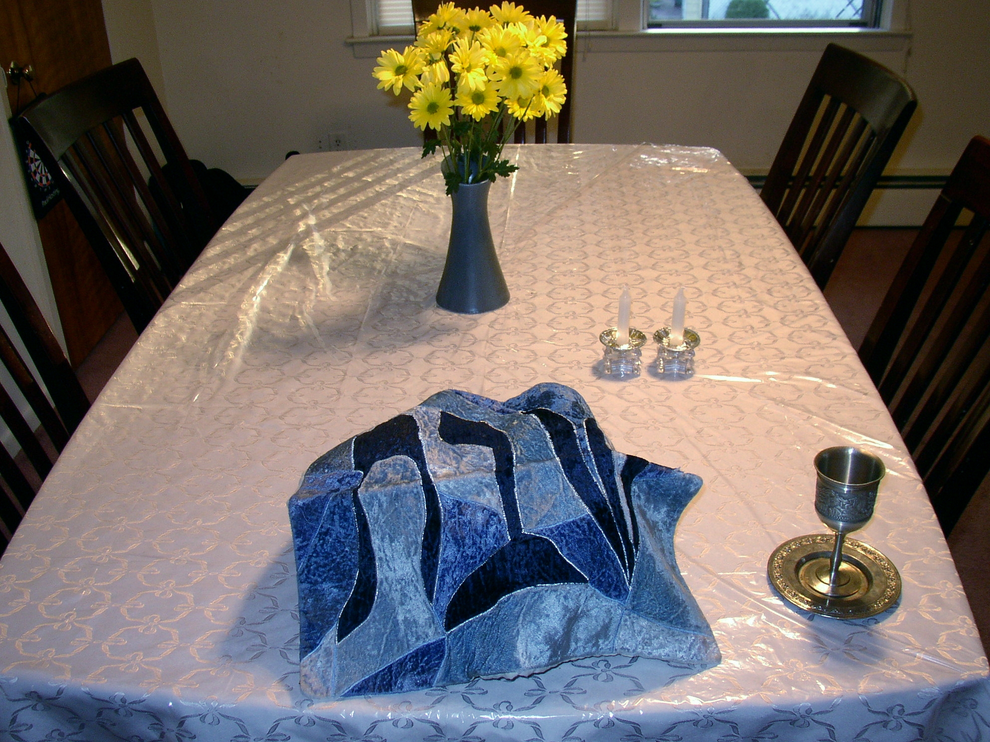 A Sabbath table with silver candlesticks and challah bread.