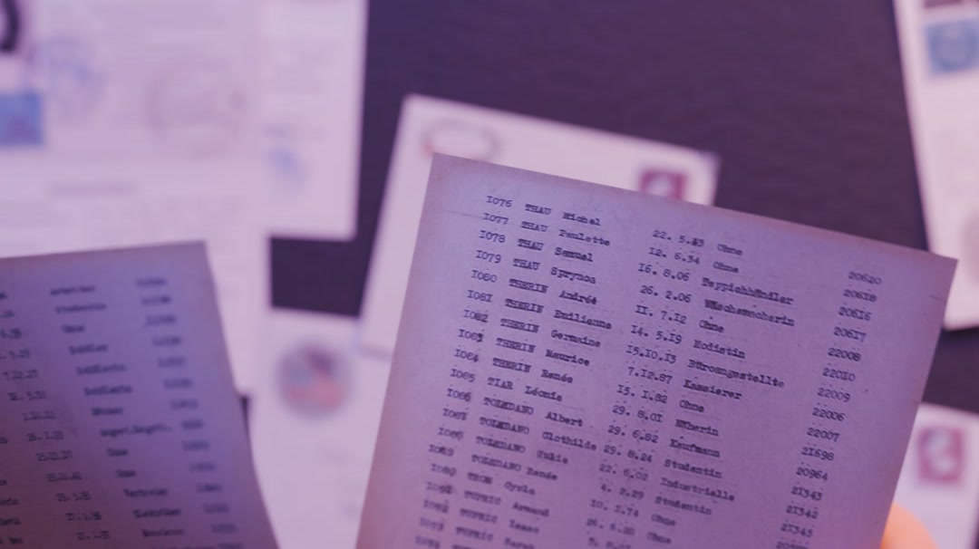 Hands holding lists of children's names, documents visible behind