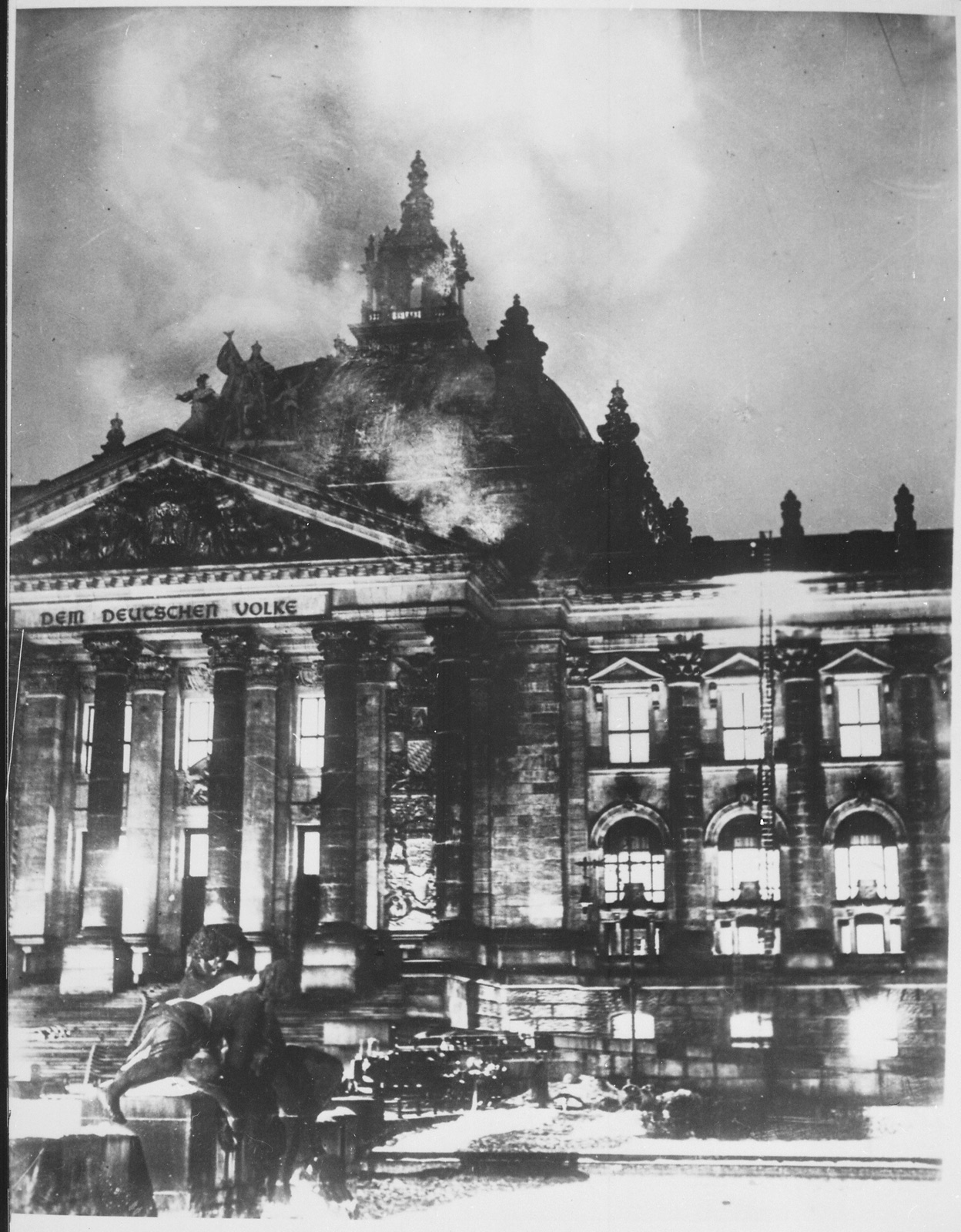 Firefighters working with hoses at the Reichstag building while it burns.