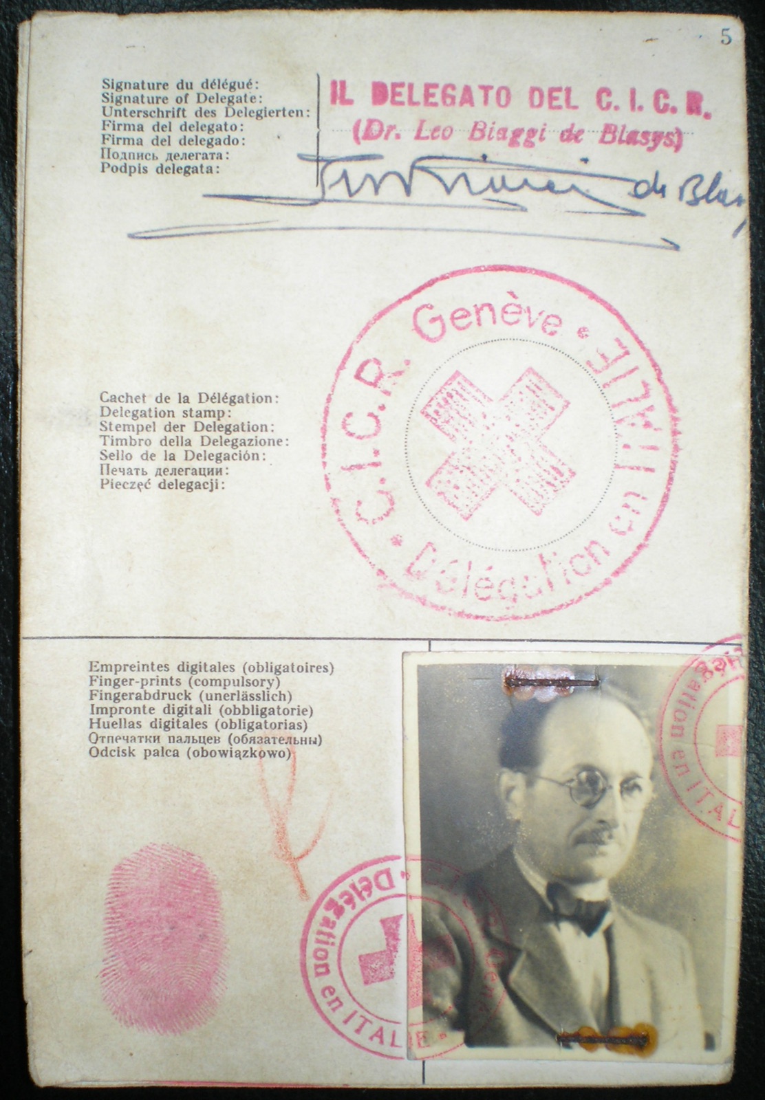 A folded Red Cross travel document opened flat, showing a passport photograph of a middle-aged man in a suit and tie, official stamps around the photograph, handwritten entries, and a fingerprint pressed in red ink below a signature.